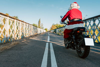 Rear view of man riding bicycle on road