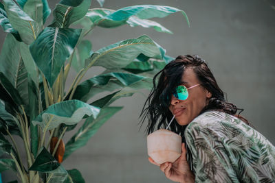 Portrait of young woman looking at plant