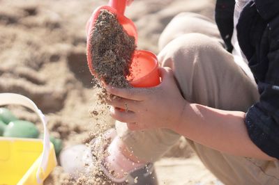 Low section of boy playing with sand at beach