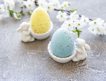 Colorful easter eggs in stand with ceramic easter bunny figurines and spring blossom 