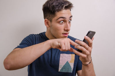 Young man using mobile phone against white background