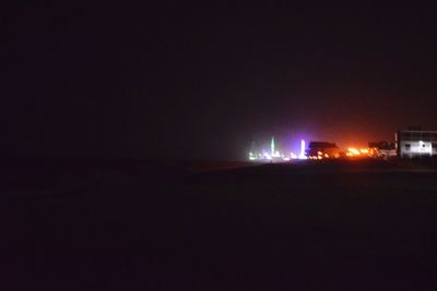 Illuminated beach against sky at night