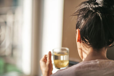 Rear view of woman holding water in cup