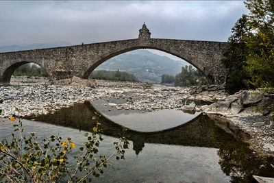 Arch bridge over river against sky