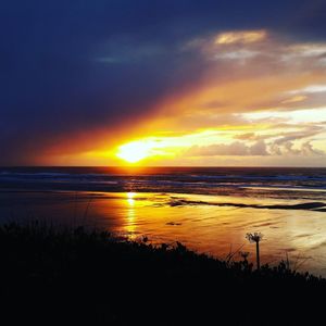 Scenic view of sea against dramatic sky during sunset