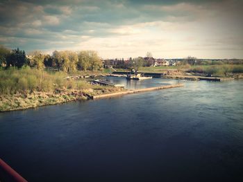 Scenic view of river against cloudy sky