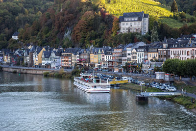 Sailboats moored on river by buildings in city