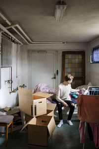 Full length of man sitting on bed while relocating new house