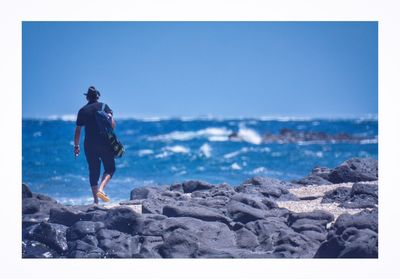 Full length of man standing on beach against clear blue sky