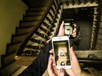 Cropped hand of women photographing staircase with mobile phones