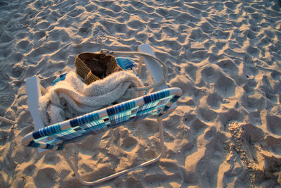 High angle view of chair and towel on sand at beach