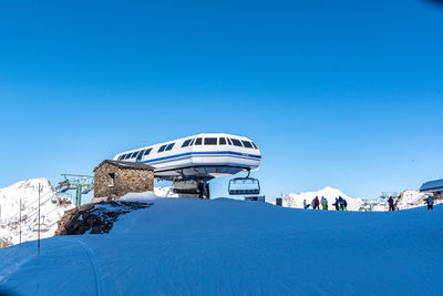 Built structure on snowcapped mountain against clear blue sky