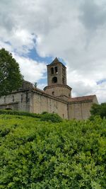 Low angle view of cross by building against sky