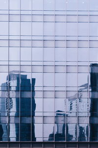 Reflection composite image of glass building against sky