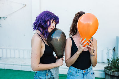 Lesbian couple holding balloon standing outdoors