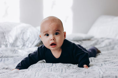 Portrait of cute boy lying on bed at home