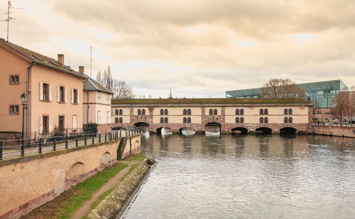 Bridge over river by buildings in city against sky