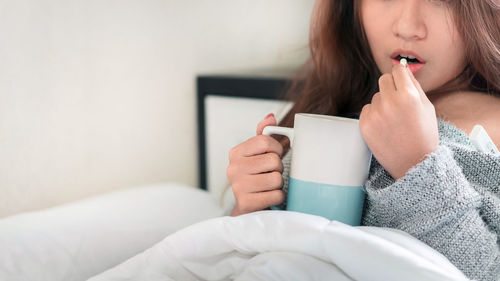 Midsection of woman sitting on sofa at home