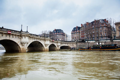 Bridge over river against sky in city