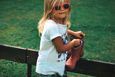 Portrait of girl wearing sunglasses standing by railing