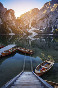 Boats moored on lake against mountains