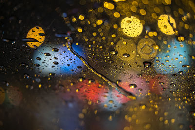 Close-up of wet car window during rainy season at night