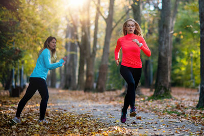 Woman exercising in public park with personal trainer in the fall