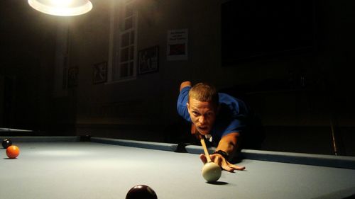 Young man playing pool against wall