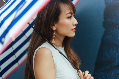 Portrait of young woman looking away against wall