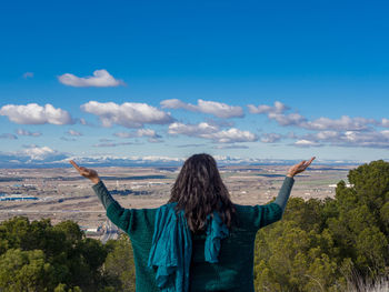 Rear view of young woman standing against sky