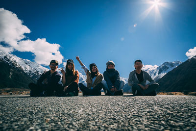 People sitting on mountain road against blue sky