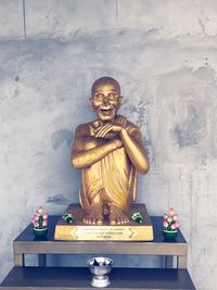 Statue on table against wall