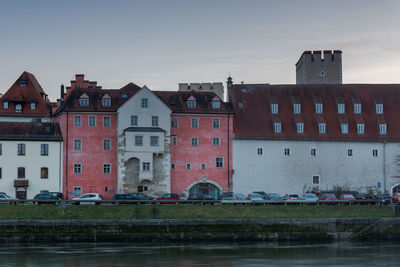 Buildings by river against sky at dusk