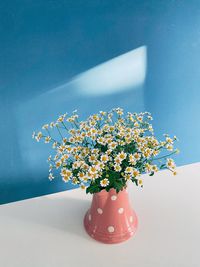 Close-up of flowering plant in vase on table against wall