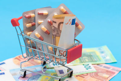 Close-up of paper currency in shopping cart against blue background