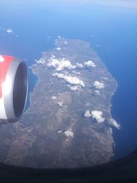 Aerial view of airplane wing over landscape against sky
