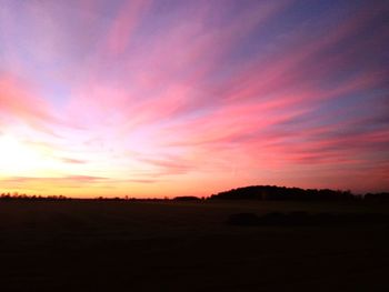 Scenic view of dramatic sky over silhouette landscape during sunset