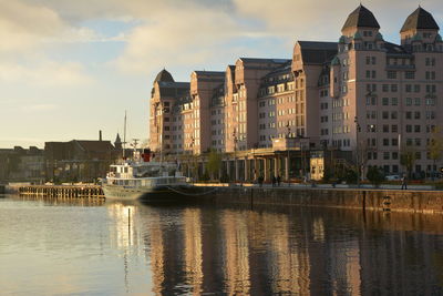 Buildings by river against sky in city