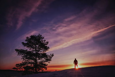 Silhouette woman standing on beach against sky during sunset