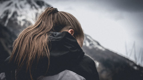 Rear view of woman with brown hair against snowcapped mountain