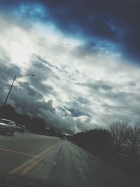 Country road against cloudy sky