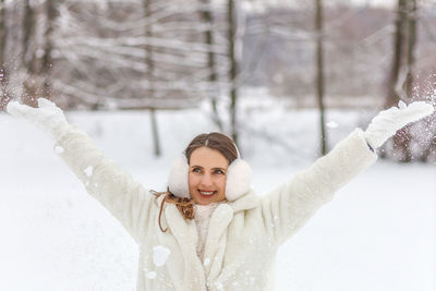 Portrait of young woman with arms outstretched standing in snow