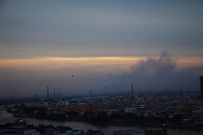 Cityscape against cloudy sky at sunset