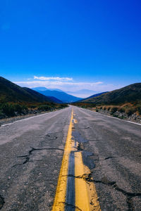 Road amidst desert against clear blue sky