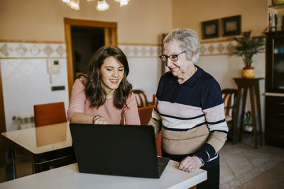 Granddaughter teaching her grandmother something on the laptop