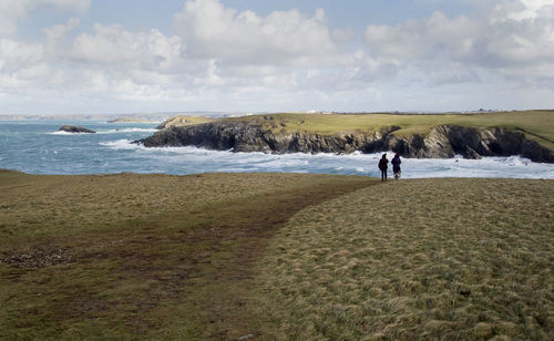 Man walking on shore by sea against sky