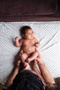 High angle cropped unrecognizable caring african american mom changing diapers on infant lying on blanket with hispanic dad