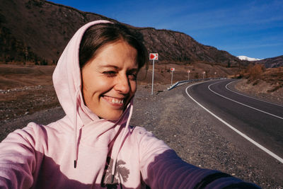 Portrait of mid adult woman on road against mountain