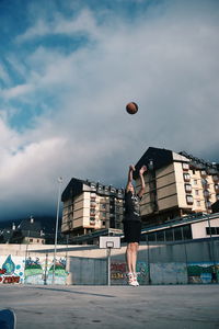 Full length of young man playing with ball against sky