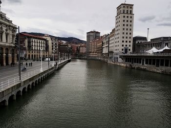 River amidst buildings in city against sky